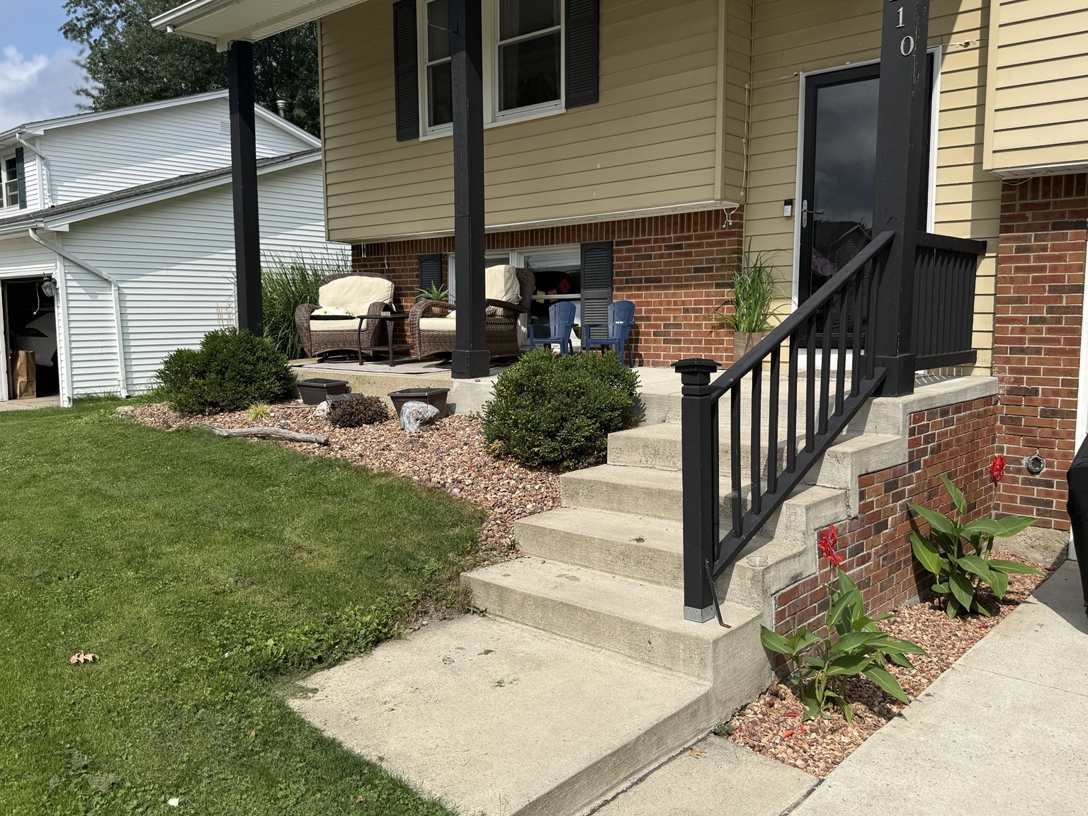Finished front-yard landscape restored with Rock-It Lite stone around shrubs, steps, and the porch